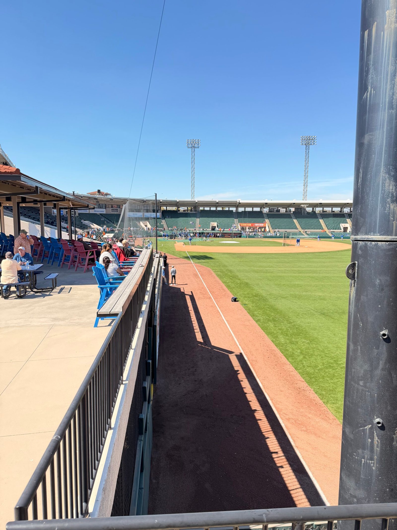 Left field foul line view with blue Adirondack chairs and pre-game warmups at Joker Marchant
